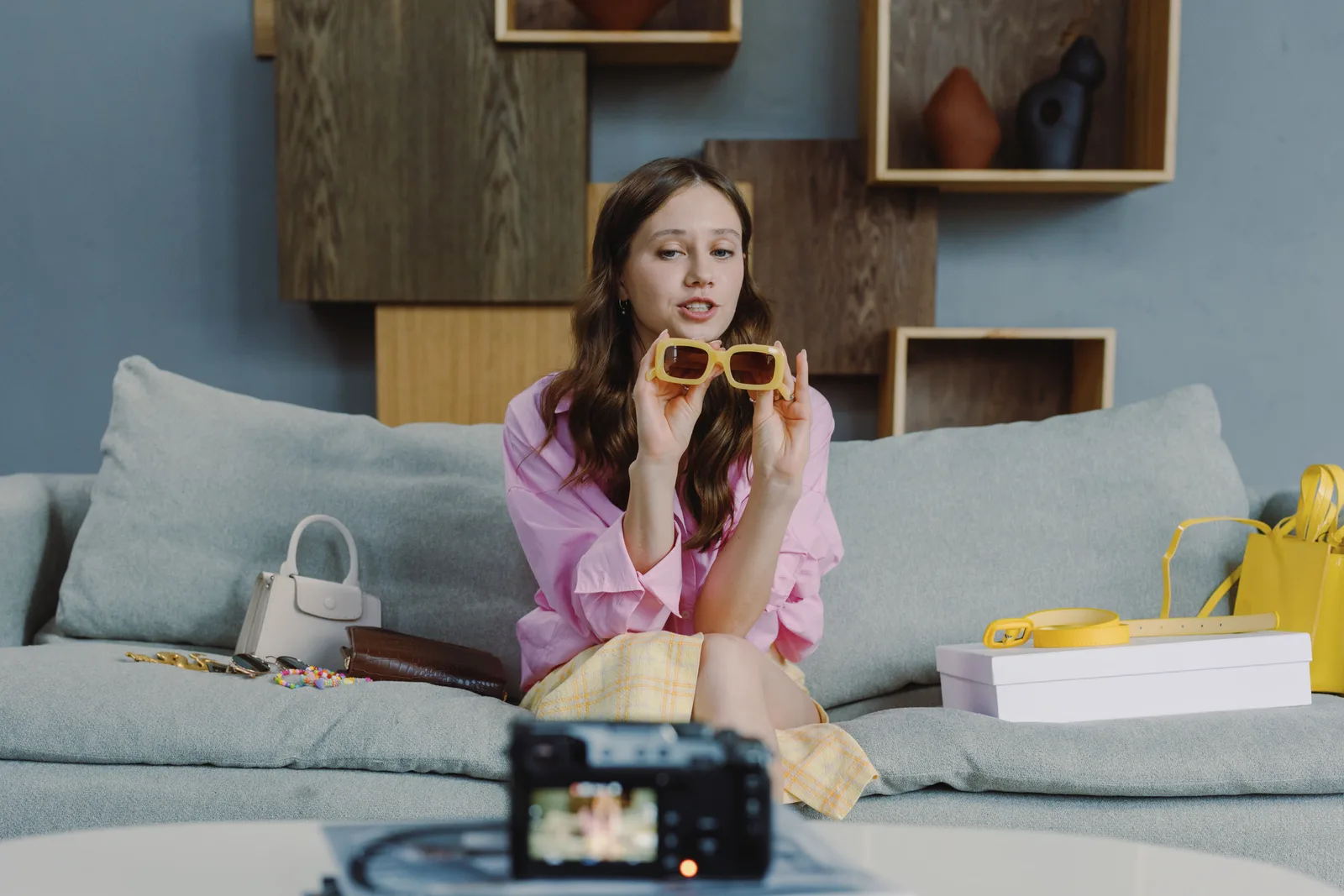 Young woman showcasing trendy sunglasses on a video blog at home.