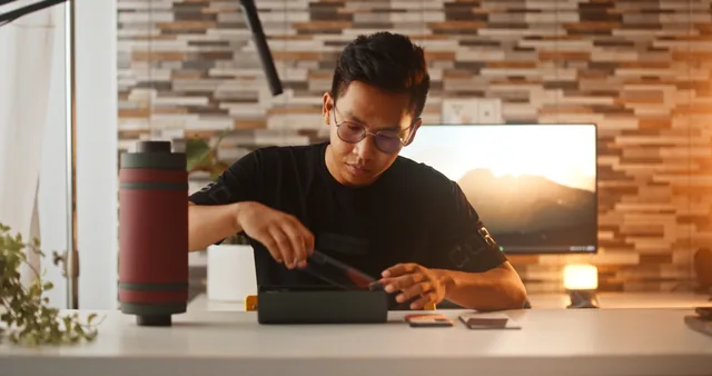 A young man unboxes a smartphone, showcasing modern technology in a cozy indoor setting. Invio di prodotti e seeding