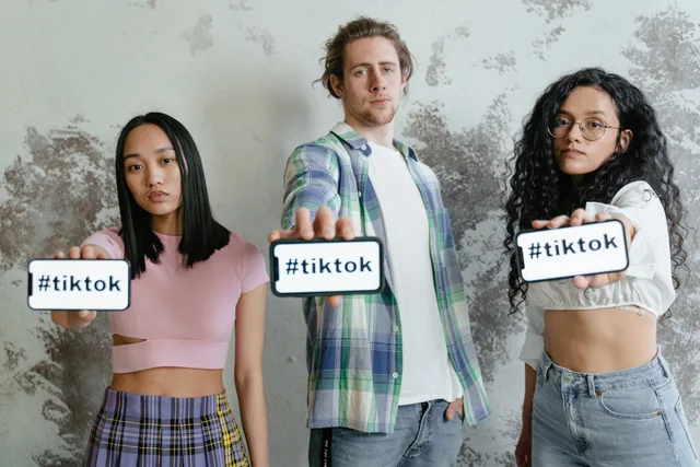 Diverse group of young adults holding smartphones displaying #tiktok hashtag. Leggere una crescita insolita dei follower