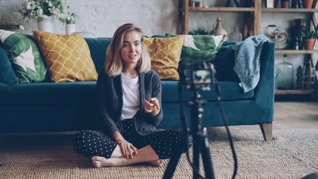 A young woman creating a vlog from her cozy living room with a camera setup. Valutare i commenti senza inventare diagnosi di frode